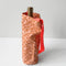 light tan wine bag with terracotta abstract checkers and red woven strap