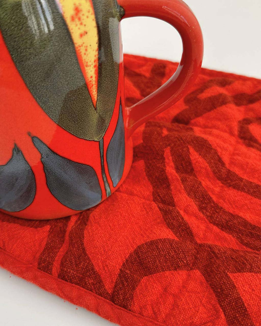 red potholder with dark red squiggle print with cup on it
