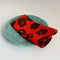 set of two red cloth napkins with black abstract flowers on plate 