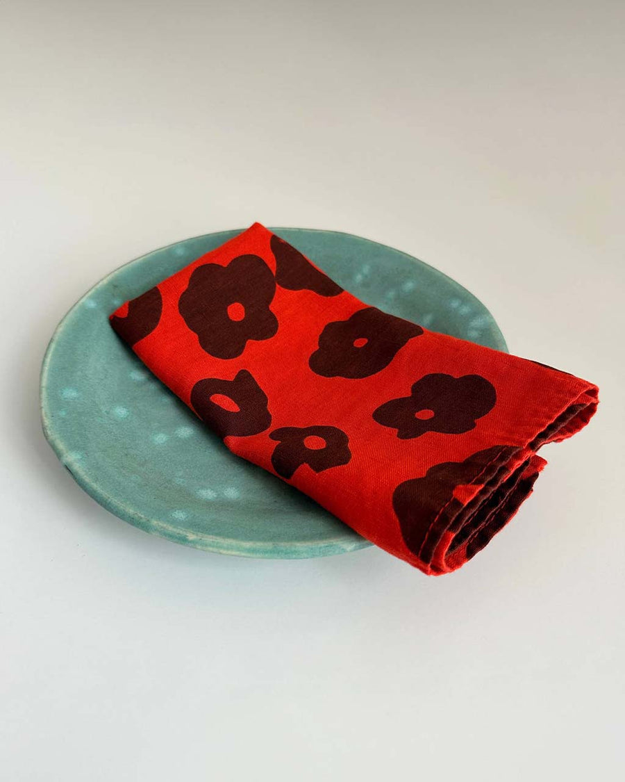 set of two red cloth napkins with black abstract flowers on plate 