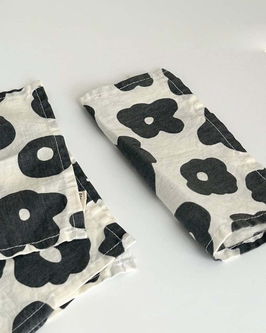 up close of set of 4 cocktail napkins with natural ground and black abstract floral print