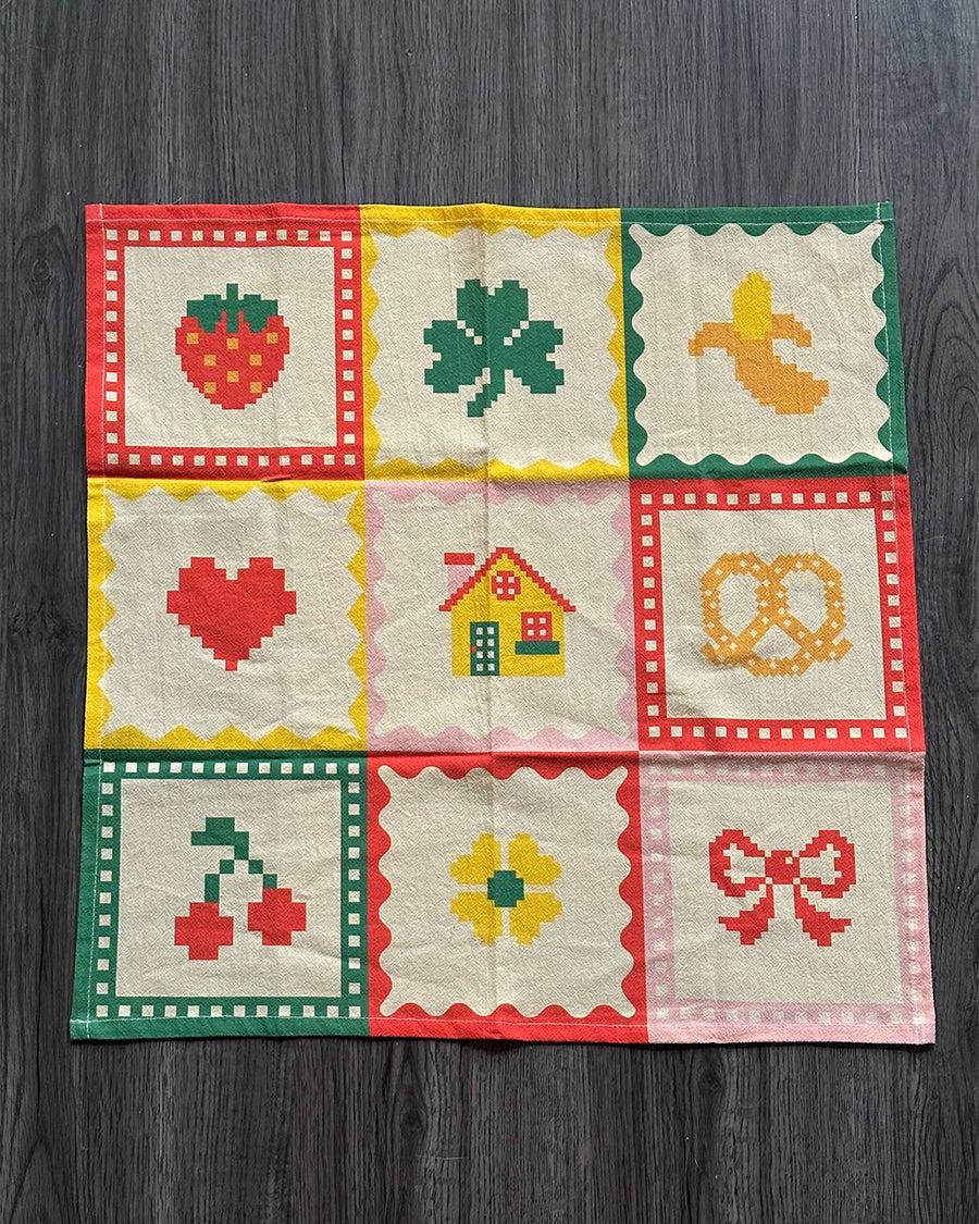 cream tea towel with strawberry, shamrock, banana, heart, house, pretzel, cherry, flower and bow icons