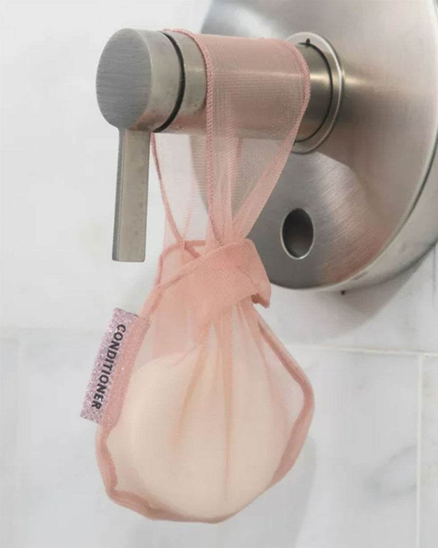 coral conditioner bar bag with bar hanging on shower faucet