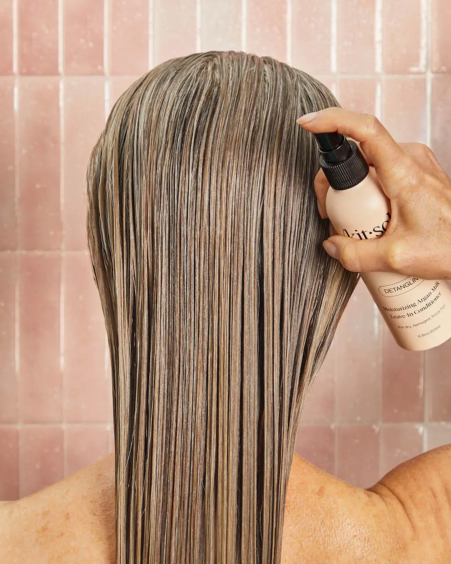 model spraying Moisturizing Argan Milk Leave-in Conditioner in their hair