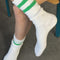 model wearing white crew socks with two kelly green stripes on the top