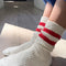 side view of model wearing white crew socks with two red stripes on the top