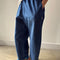 side view of model wearing cotton denim blue pants with workmen patches down the front and inner drawstring