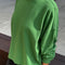 side view of model wearing asparagus long sleeve tee with elastic arm bands and relaxed fit