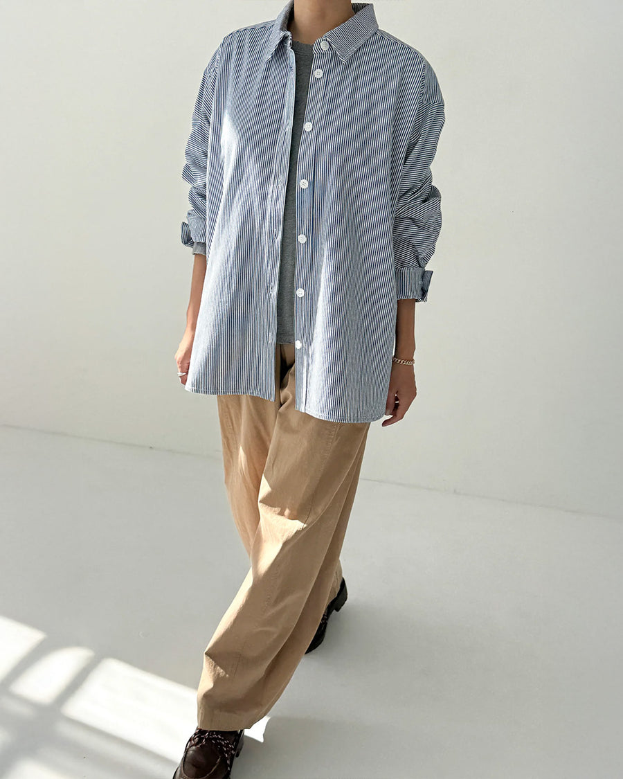 model wearing blue and white vertical pinstripe denim button up shirt and khaki pants