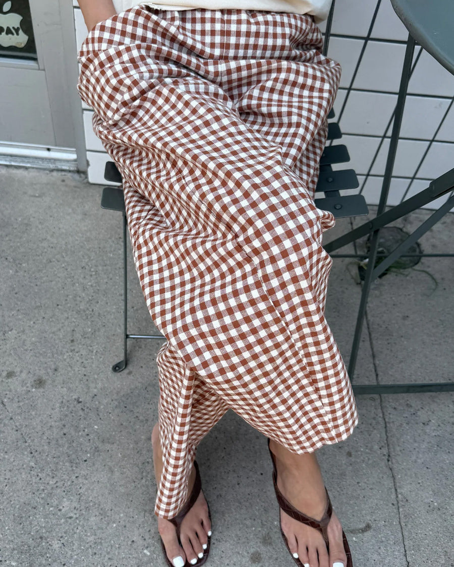model wearing rust and white gingham relaxed fit pants while sitting