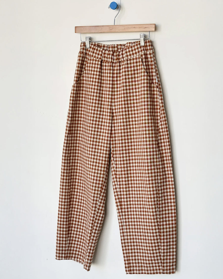 rust and white gingham relaxed fit pants on a hanger