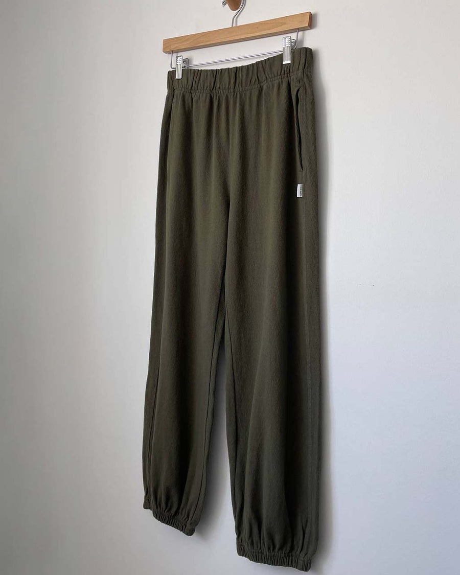 olive green cotton pants on a hanger
