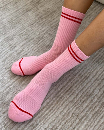 model wearing bright pink tube socks with red stripe detail
