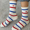 model wearing white socks with red and blue multiple stripe socks with embroidered red heart