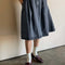 model wearing black denim midi skirt with button closure and pleated front