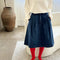 model wearing black denim midi skirt with button closure and pleated front and red tights