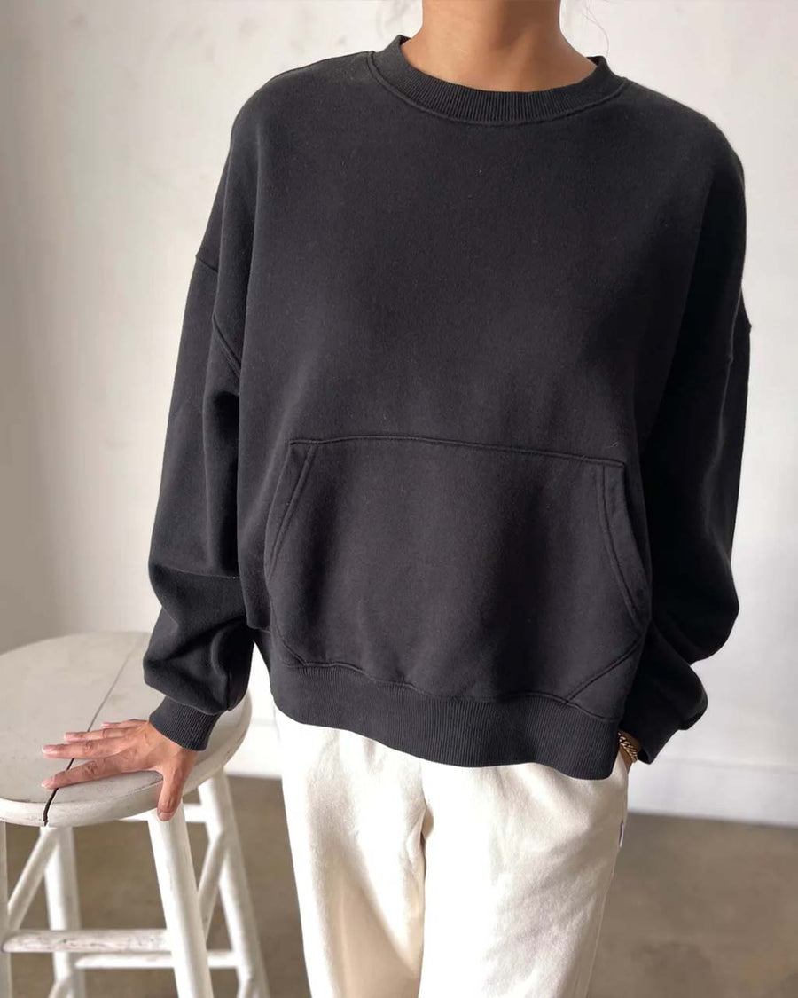 model wearing black pullover cotton sweatshirt with kangaroo pocket