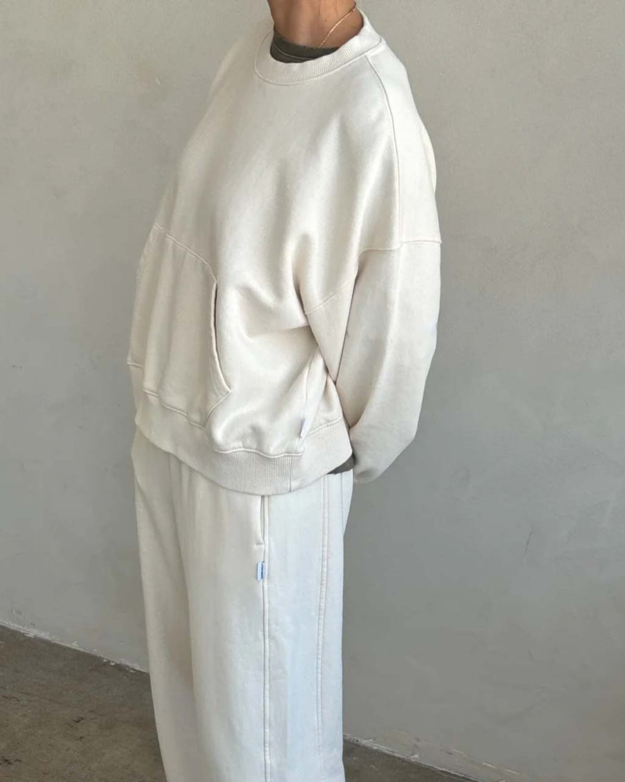 side view of model wearing cream pullover cotton sweatshirt with kangaroo pocket