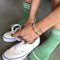 model wearing high avocado green socks with three white stripes at the top while putting on sneakers