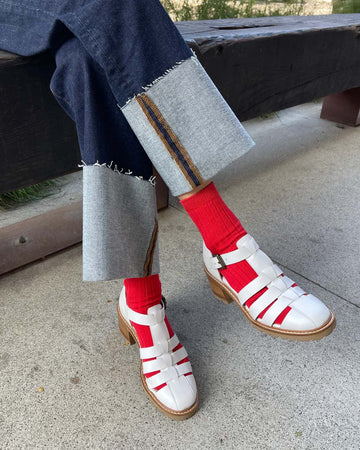 model wearing red ribbed high crew socks with white fisherman shoes
