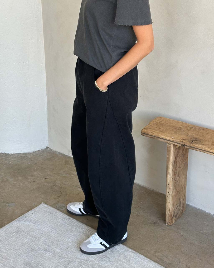 side view of model wearing black canvas extended length arc pants