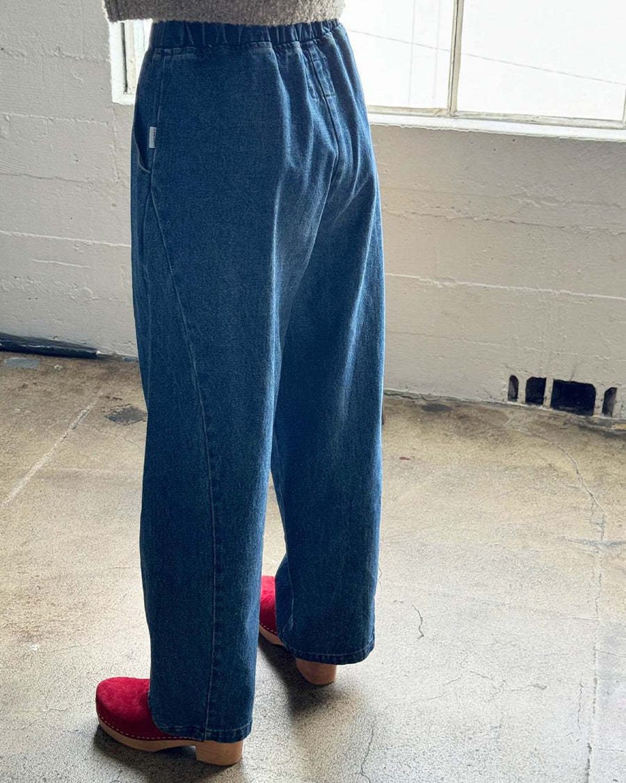 back view of model wearing blue denim extended length arc pants