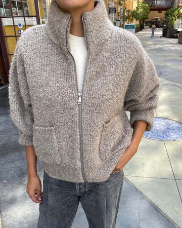 model wearing zipped taupe grey fluffy jacket with collar, zip front and patch pockets