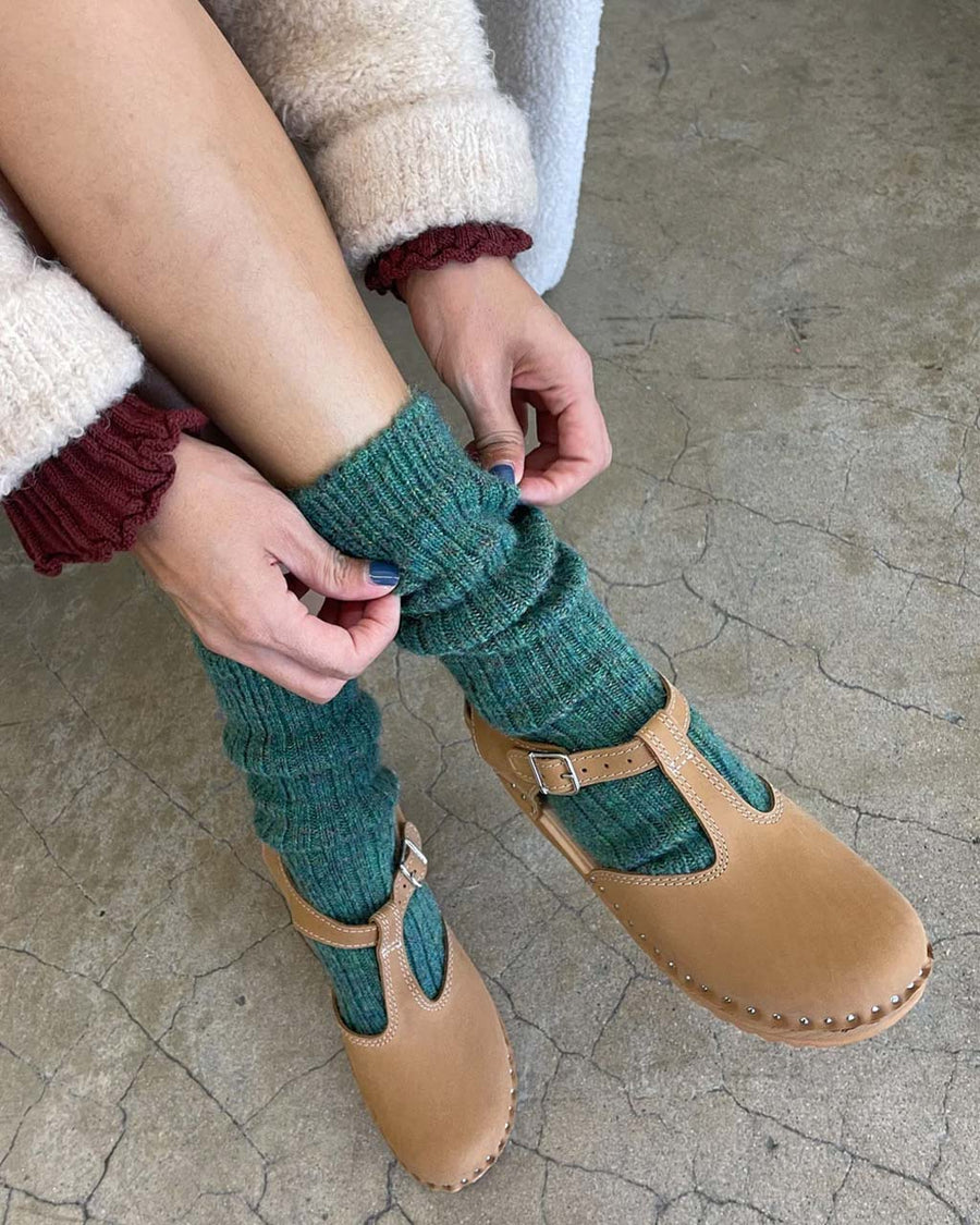 model wearing high crew fuzzy emerald socks with brown flats