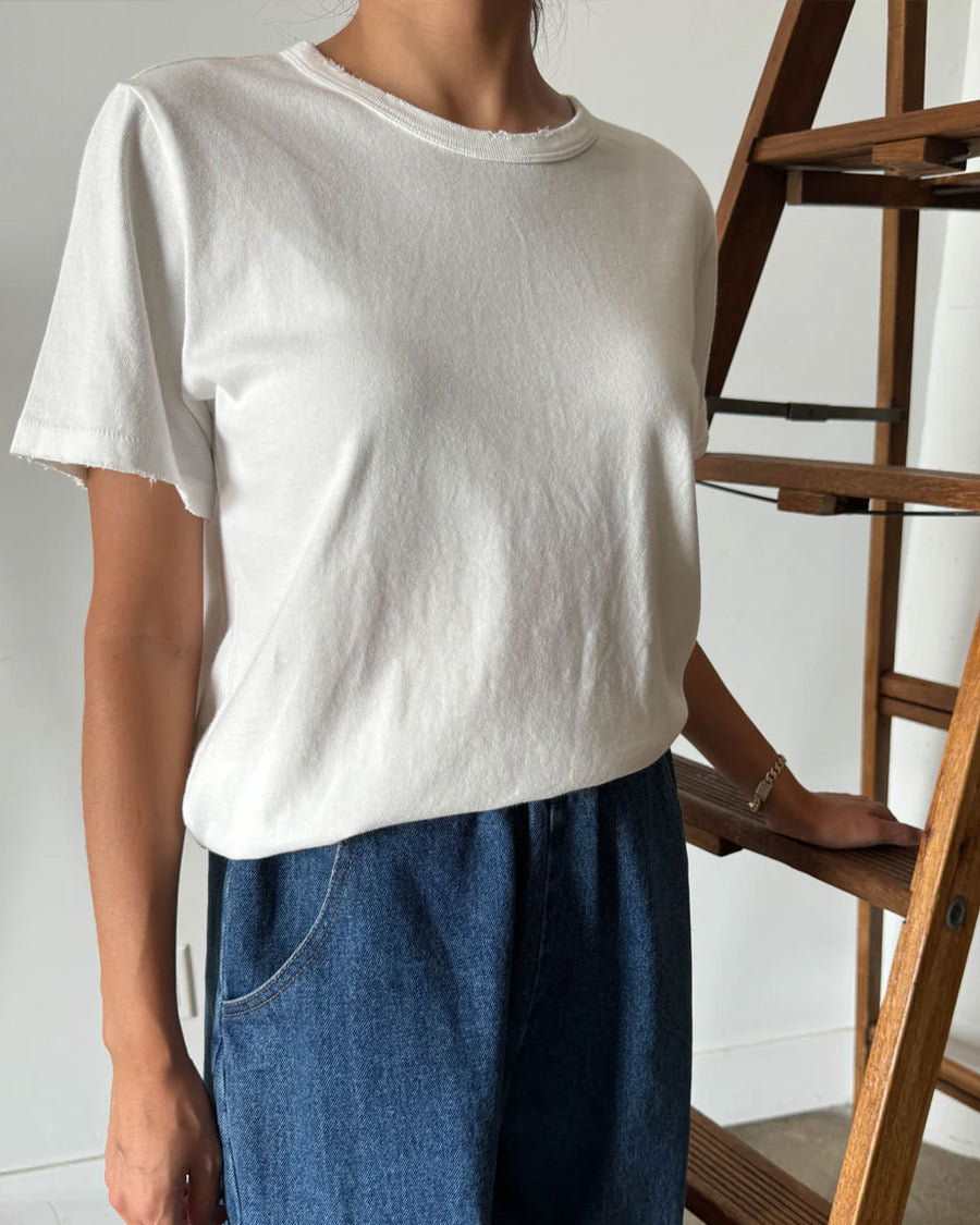 model wearing white organic cotton tee with slight distressing on the sleeves and neckline