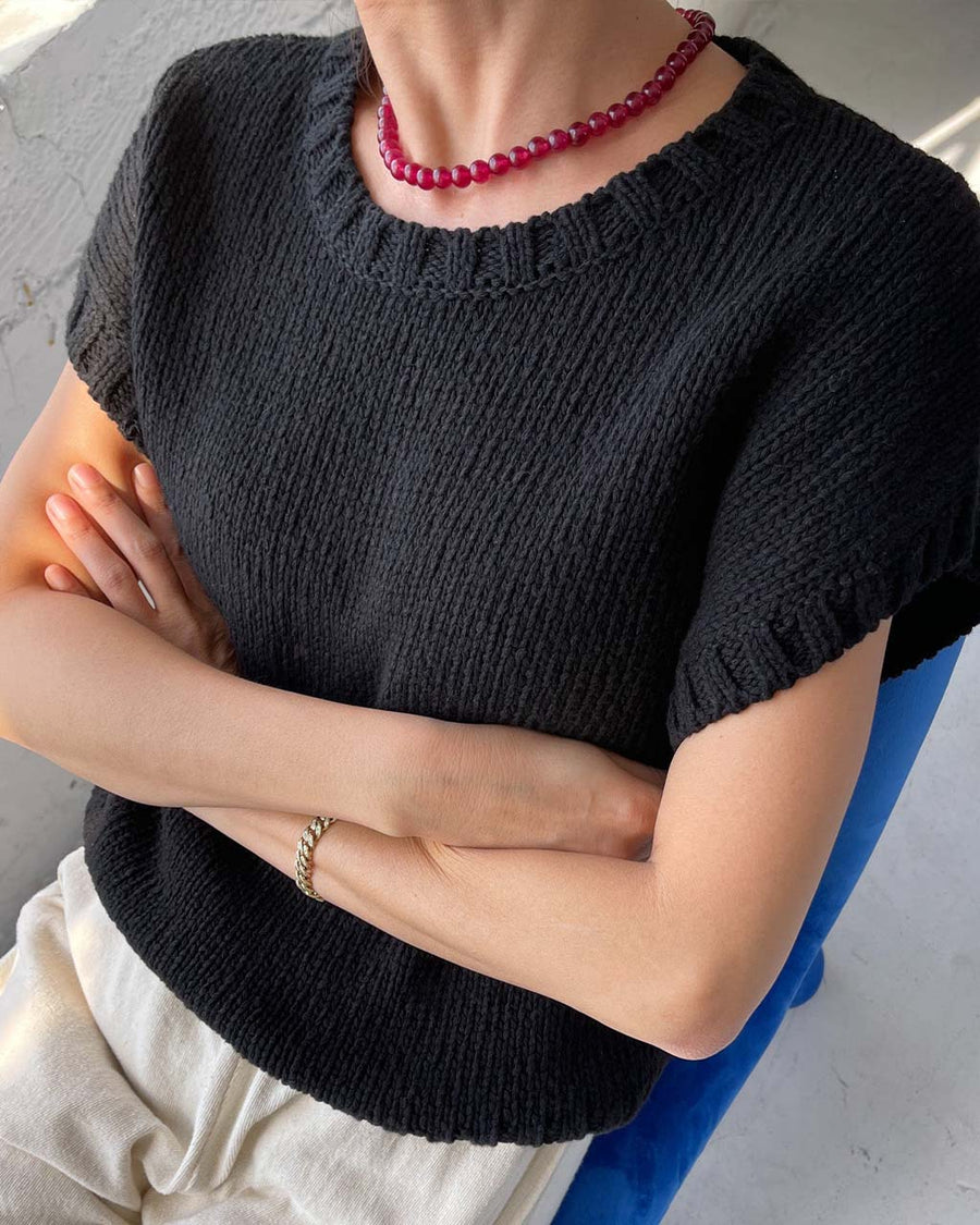 up close of model wearing black short sleeve sweater top with denim