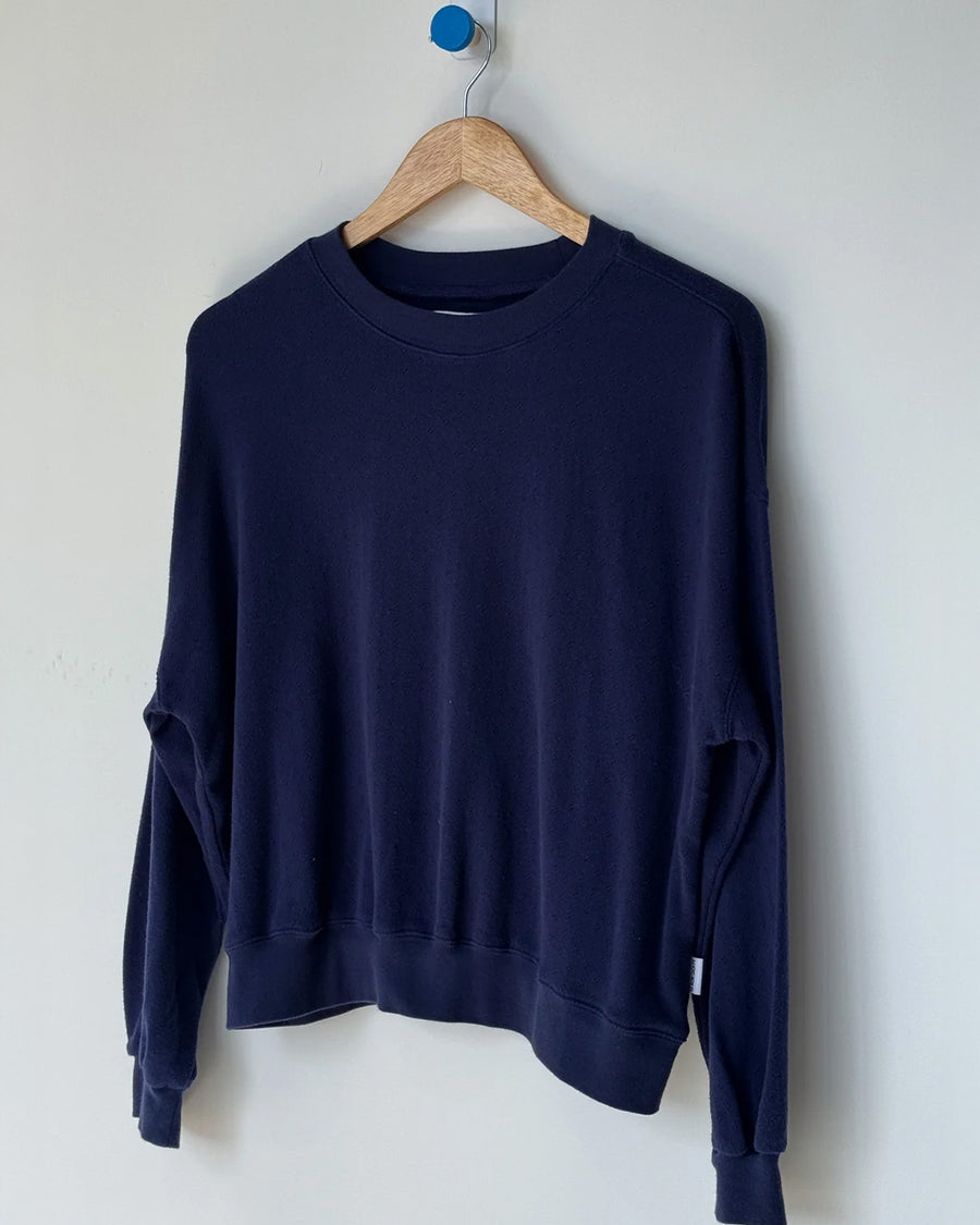 navy pointelle sweatshirt with banded bottom on a hanger