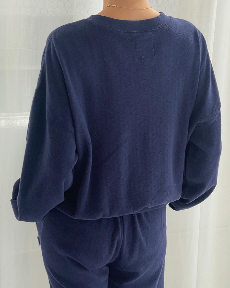 back view of model wearing navy pointelle sweatshirt with banded bottom