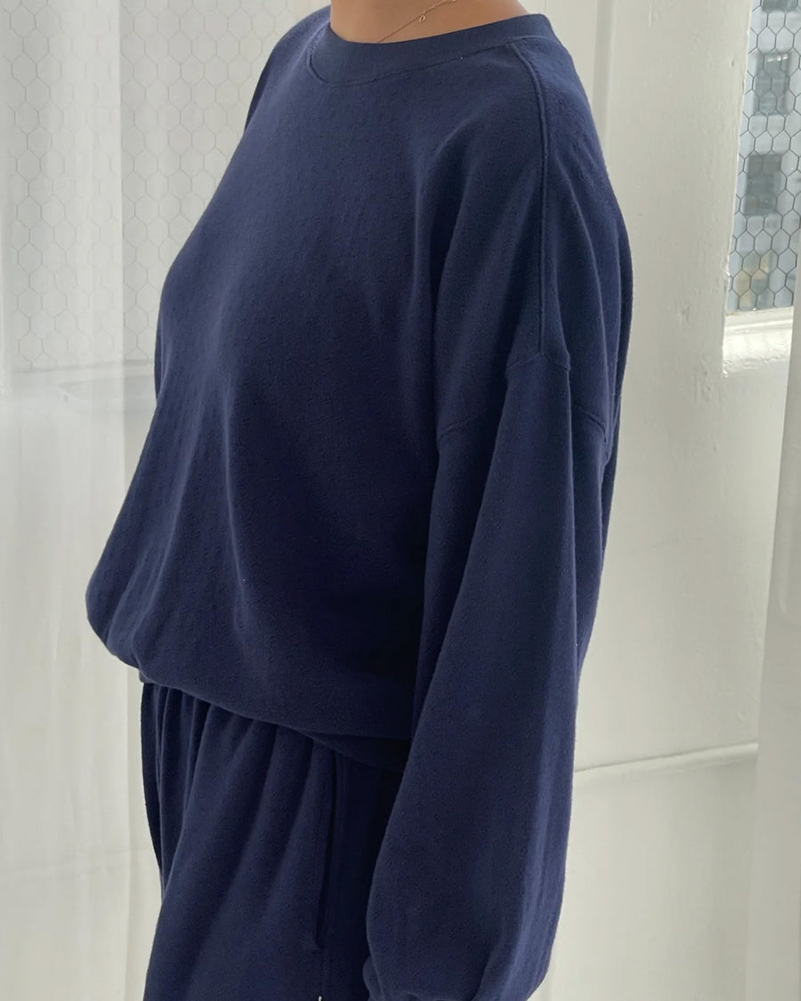 side view of model wearing navy pointelle sweatshirt with banded bottom