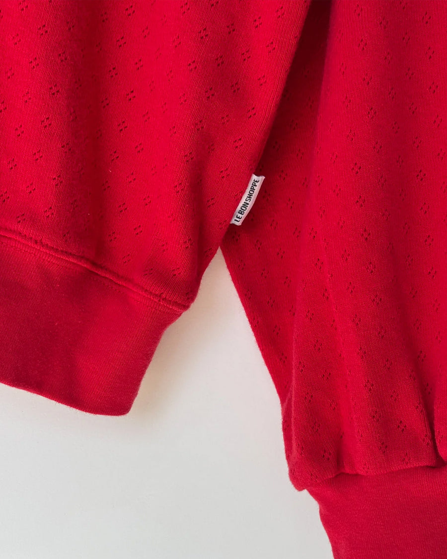 up close of candy apple red pointelle sweatshirt with banded bottom