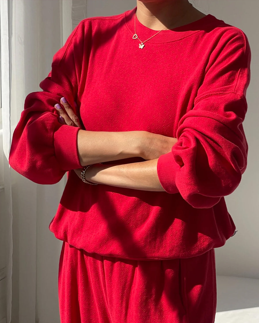 model wearing candy apple red pointelle sweatshirt with banded bottom