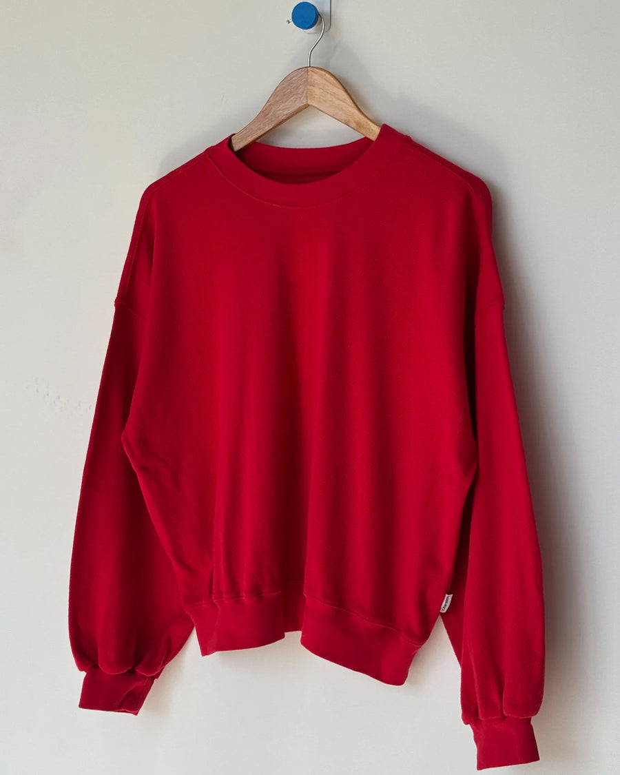 candy apple red pointelle sweatshirt with banded bottom on a hanger