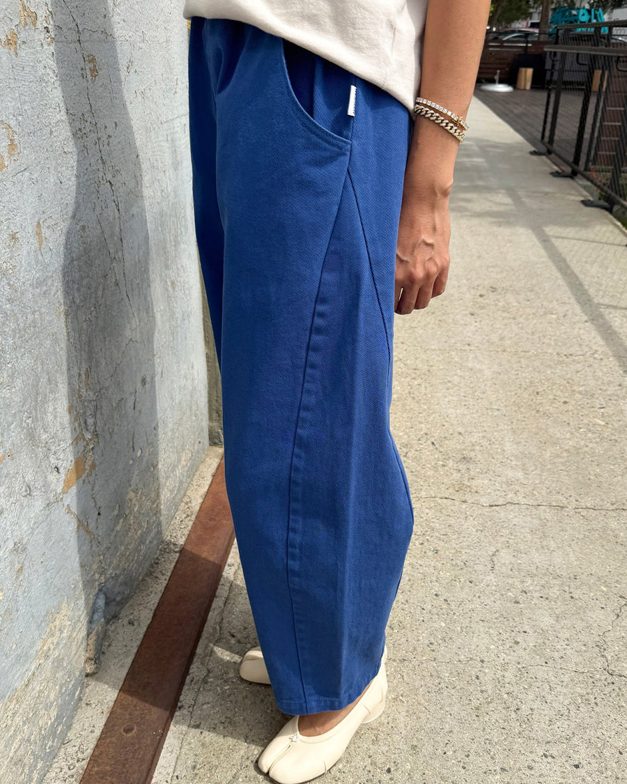 side view of model wearing blue azure arc pants with side pockets and side leg panels