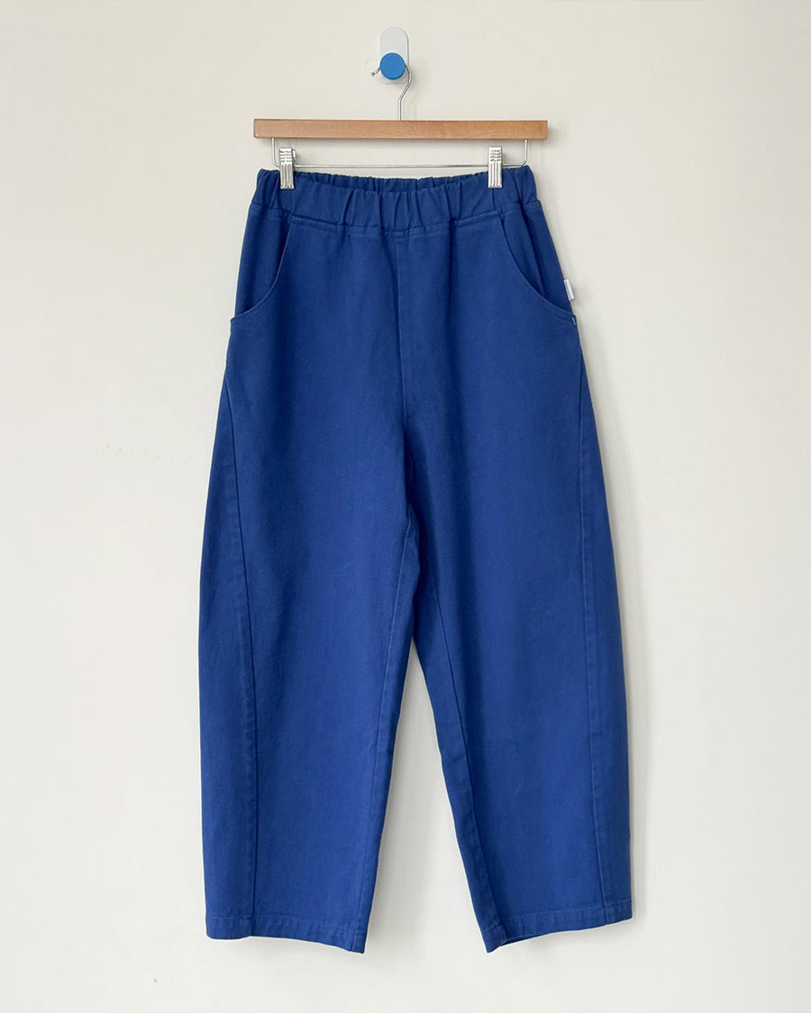 blue azure arc pants with side pockets and side leg panels on a hanger