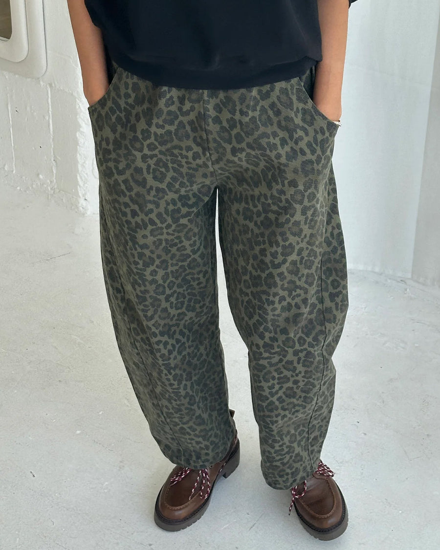 model wearing greenish leopard print arc pants with side pockets and side leg panels