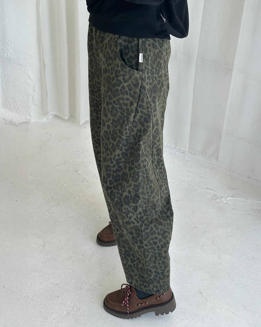 side view of model wearing greenish leopard print arc pants with side pockets and side leg panels
