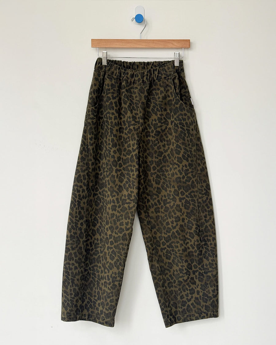 greenish leopard print arc pants with side pockets and side leg panels on a hanger