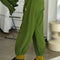 side view of model wearing avocado green cotton balloon pants with side pockets