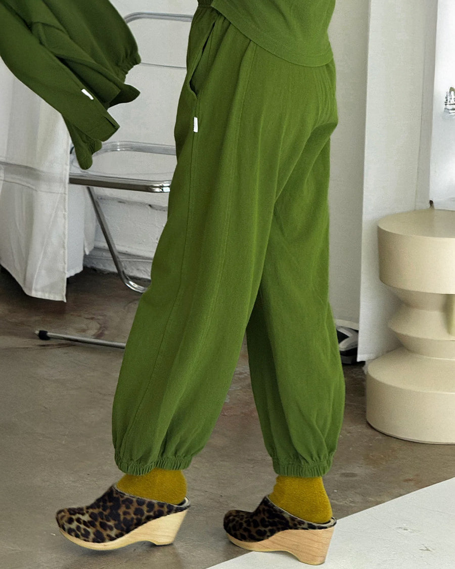 side view of model wearing avocado green cotton balloon pants with side pockets