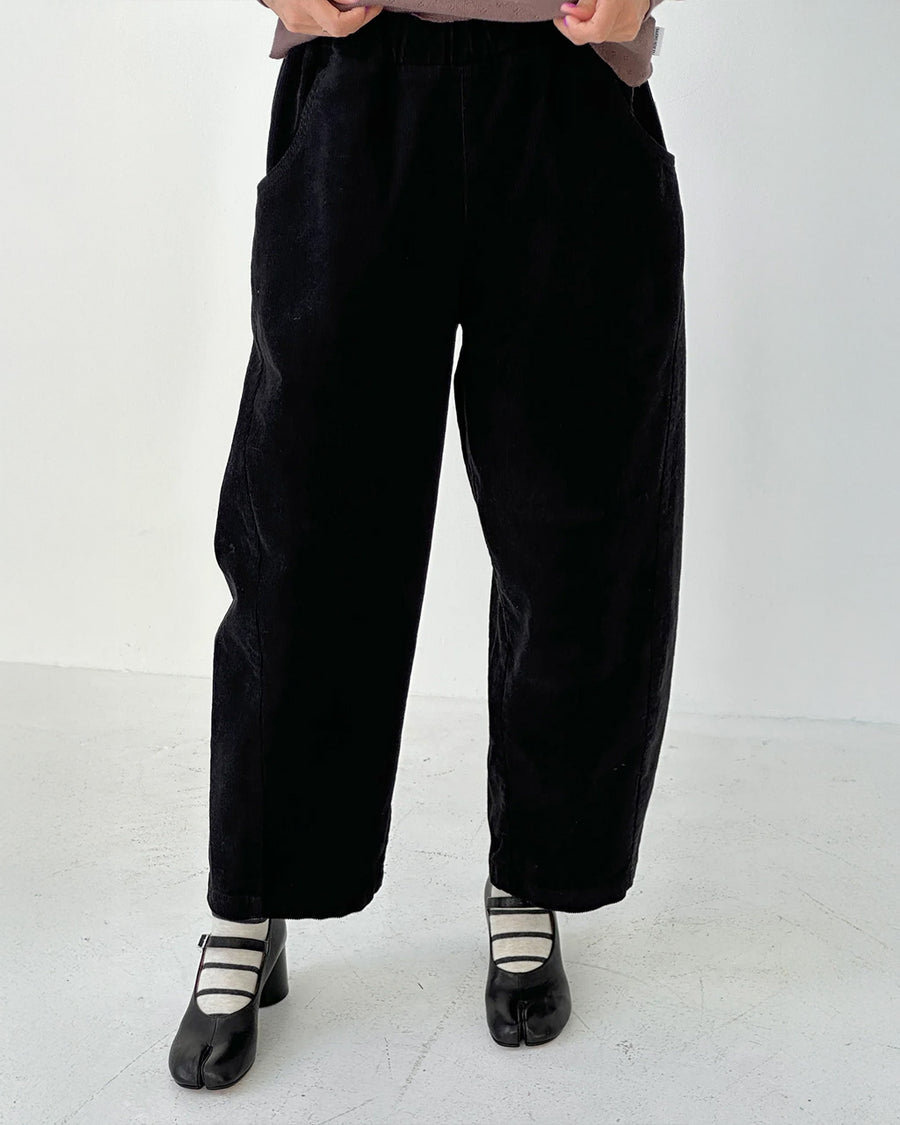 model wearing black corduroy arc pants with side panels and pockets