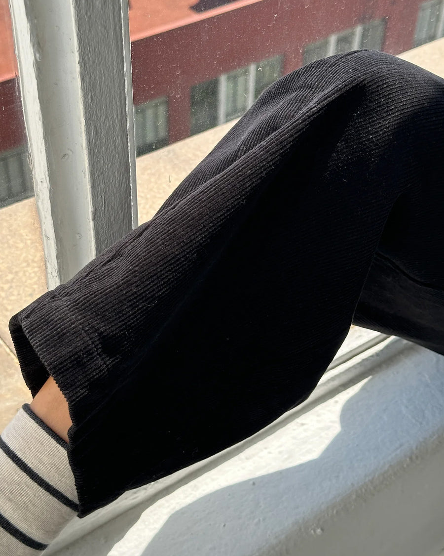 up close of model wearing black corduroy arc pants with side panels and pockets
