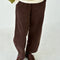 model wearing chocolate brown corduroy arc pants with side panels and pockets