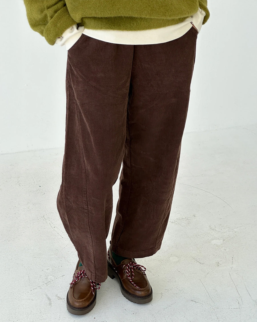 model wearing chocolate brown corduroy arc pants with side panels and pockets