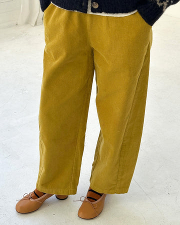 model wearing green olive corduroy arc pants with side panels and pockets
