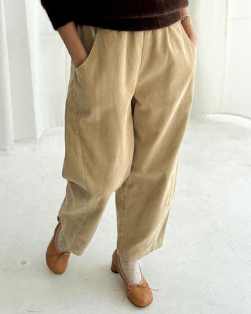 model wearing khaki corduroy arc pants with side panels and pockets