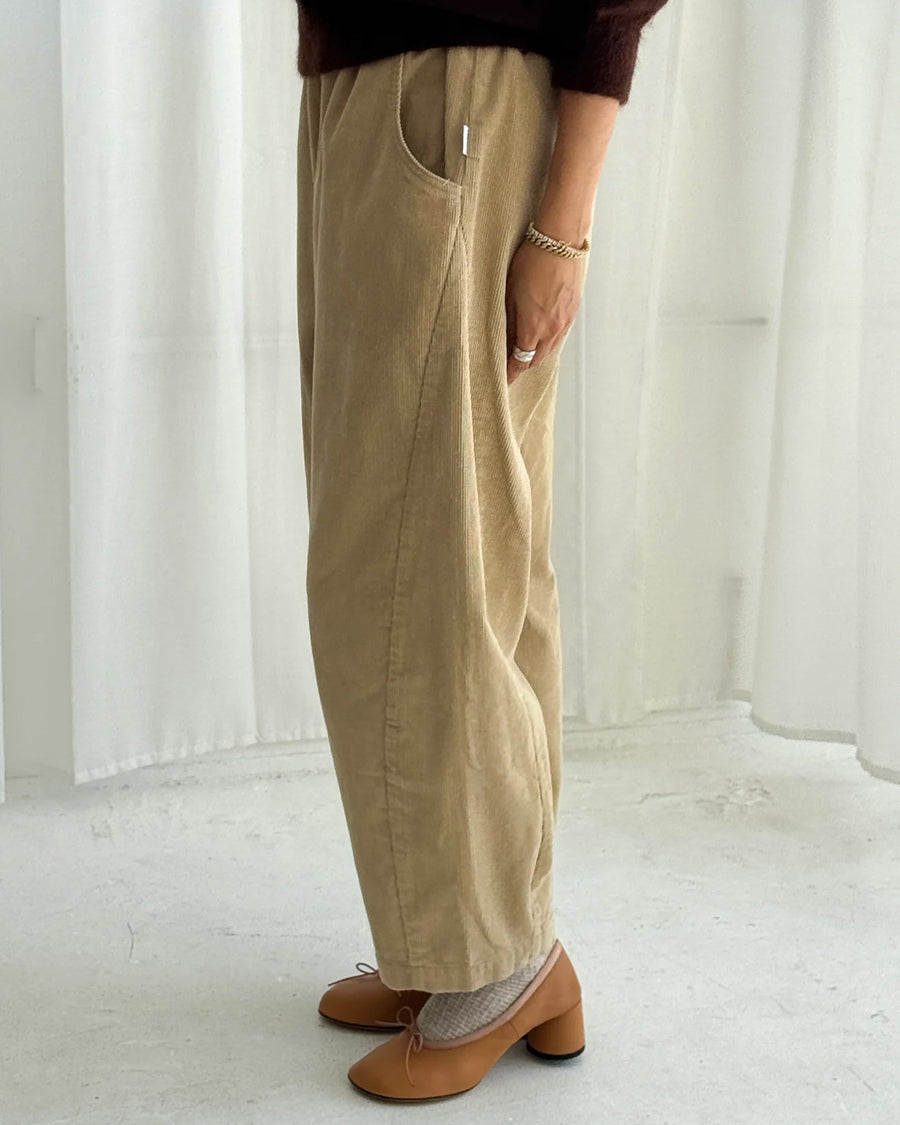 side view of model wearing khaki corduroy arc pants with side panels and pockets